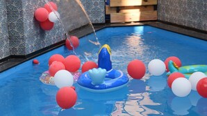 Una piscina con juguetes inflables y globos rojos y blancos.