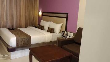 A hotel room with a bed, a nightstand, a coffee maker, and a seating area.
