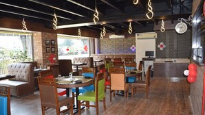 Un restaurante con cabinas y mesas, pisos de madera y lámparas colgantes.