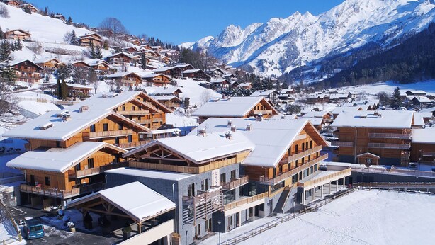 A snow-covered mountain village with wooden chalets and a ski slope.