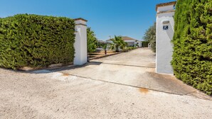 Une allée bordée de portails mène à un bâtiment à la façade blanche, avec un palmier en premier plan.
