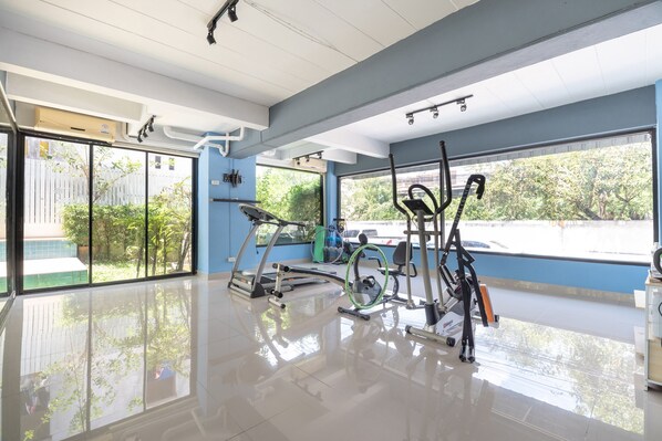 Un gimnasio amplio con diversos equipos de ejercicio, ventanas grandes y un suelo limpio y brillante.
