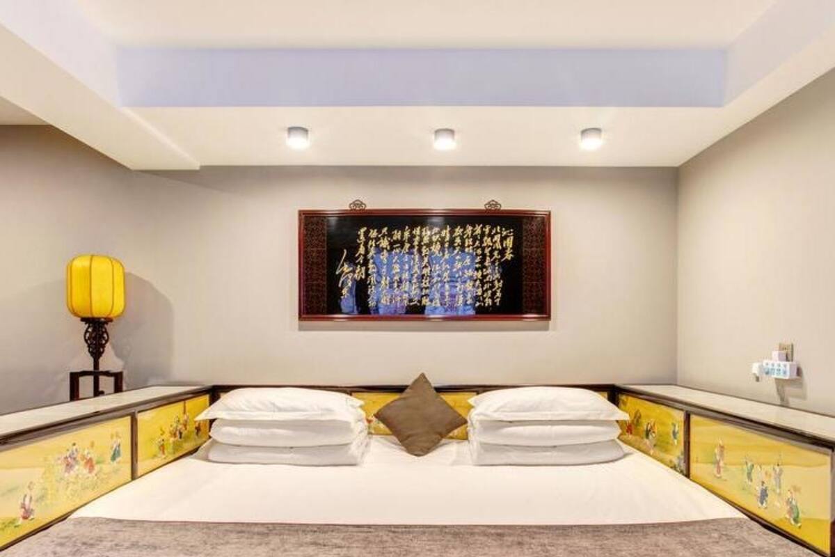 Une chambre d’hôtel avec un grand lit, deux oreillers, une table de chevet avec une lampe et une œuvre d’art accrochée au mur.