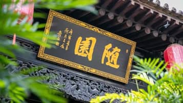 A sign with traditional Chinese characters on a black background with gold trim, mounted on a structure with ornate carvings.