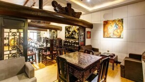 A traditional-style living room with a central ornate table, surrounded by chairs and sofas, featuring a wooden ceiling and a large abstract painting on the wall. - Floral Hotel Sui Yuan Pingyao (Jinzhong)