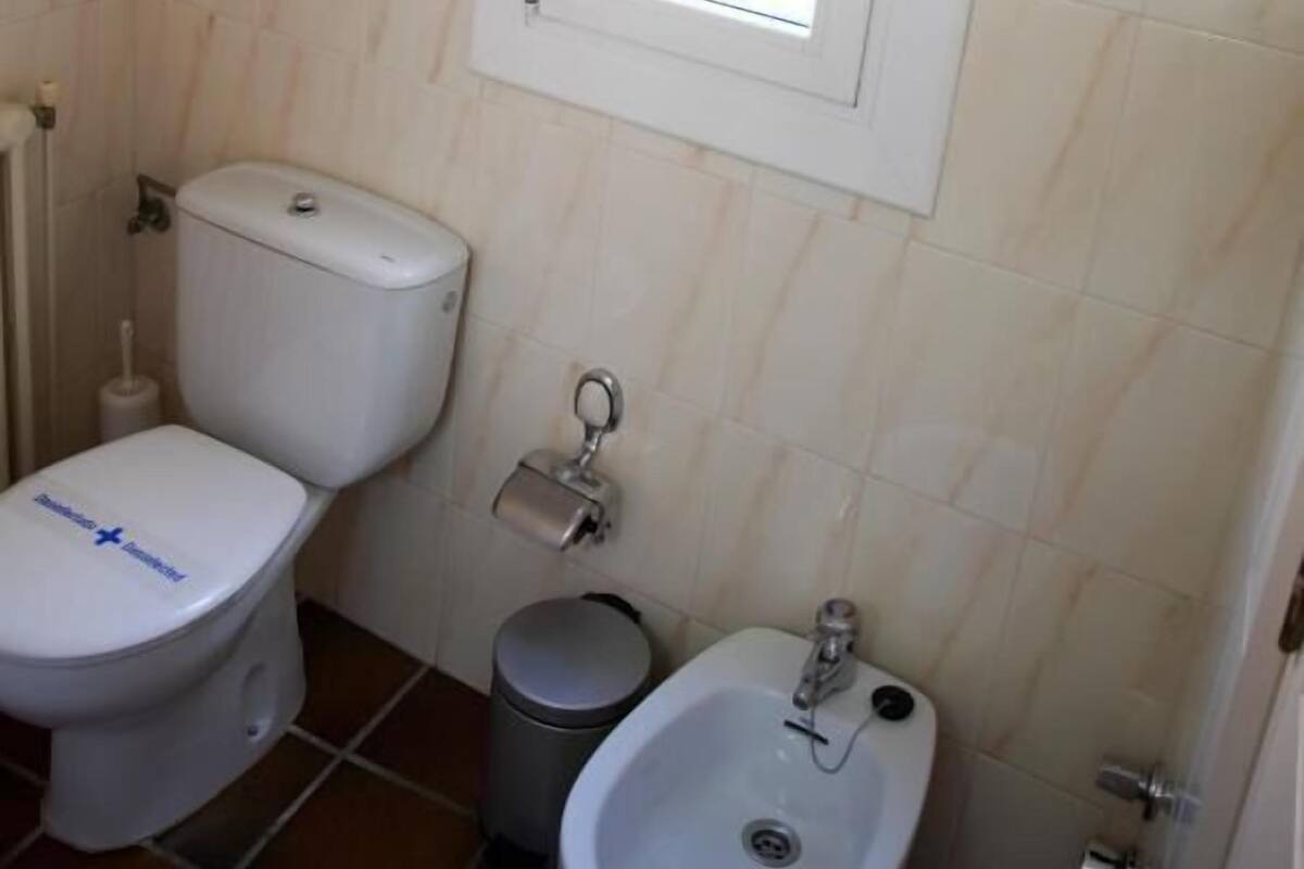 A bathroom with a toilet, bidet, and sink, all in white.