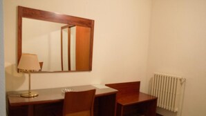 A small room with a wooden desk, two chairs, a lamp, and a mirror. - Hotel Suis (Sant Celoni)