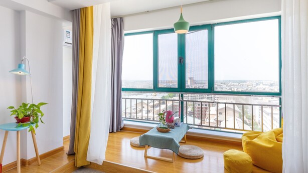 A modern living room with a large window, a small table with a plant, a yellow armchair, and a blue pendant light. - Floral Hotel Jiu Qi Yin Ju Dunhuang (Jiuquan)