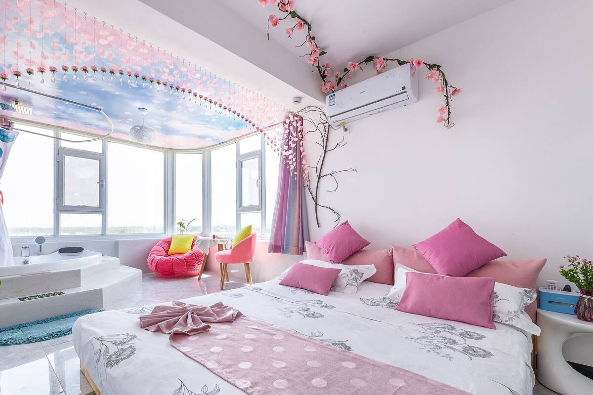 Ein Schlafzimmer mit einem großen Bett, einer Sitzecke mit einem Sessel, einer Badewanne und einem Fenster mit Blick.