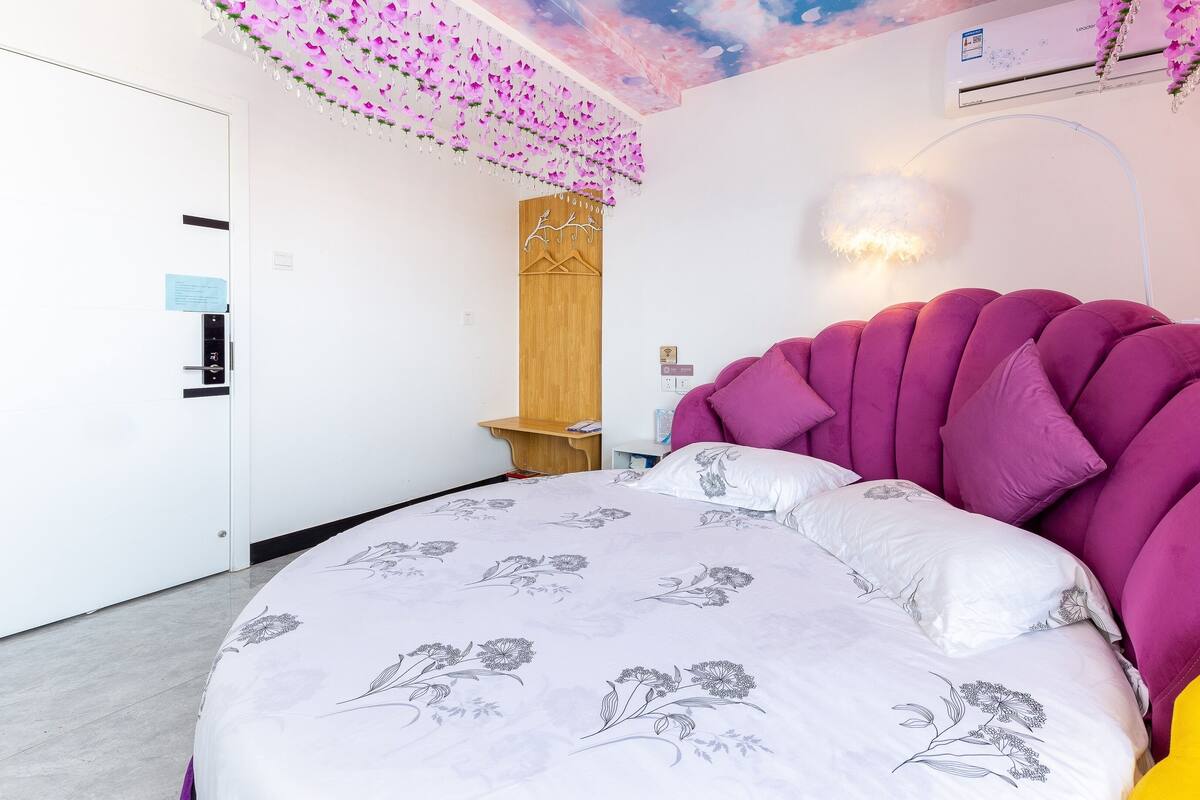 Ein Schlafzimmer mit einem großen Bett, einem Holzschrank, einem Nachttisch und einer Decke mit floralen Verzierungen.