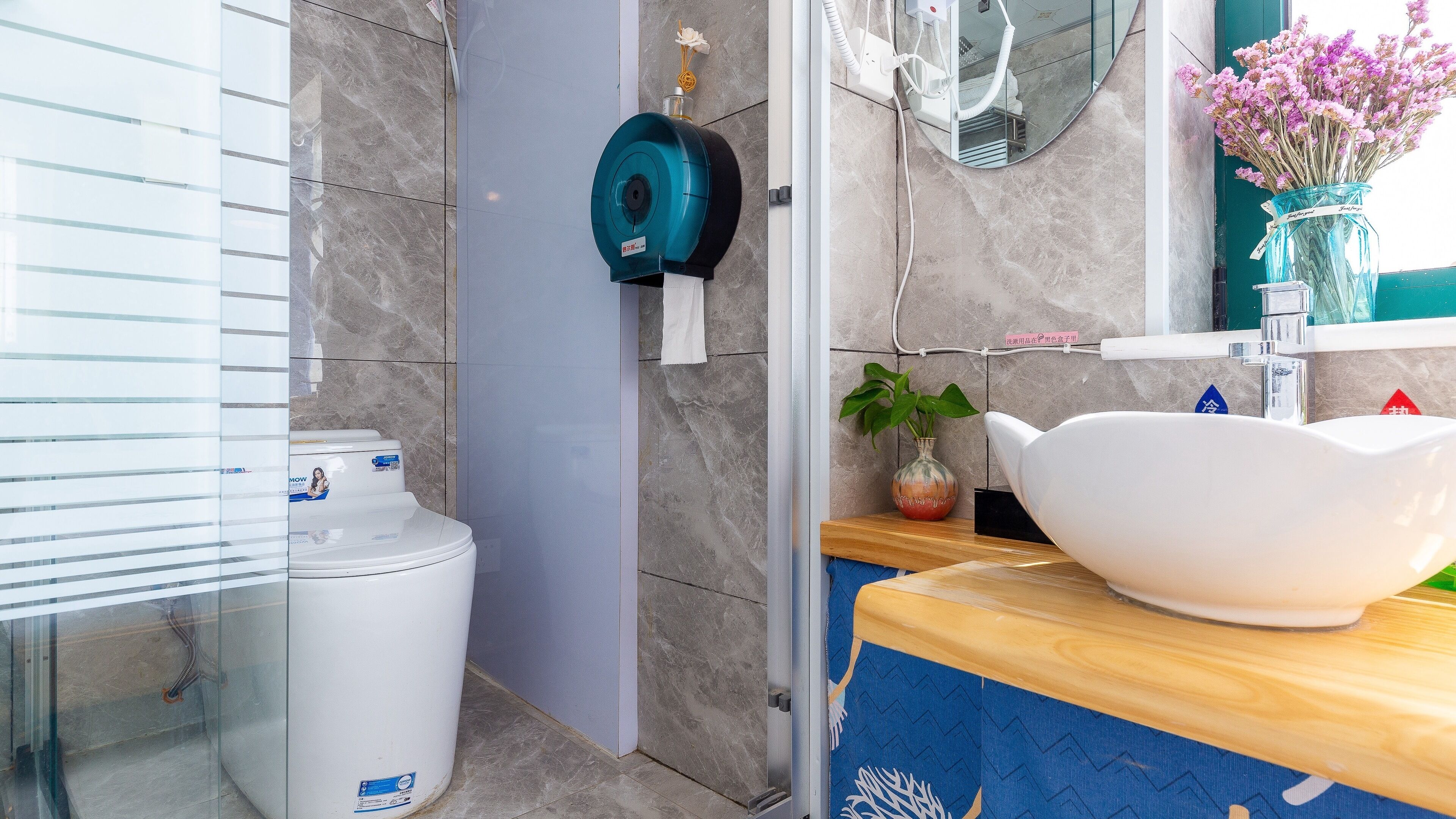 A bathroom with a white toilet, a blue water heater, a white sink, and a mirror.