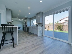 A spacious kitchen with a bar area, large windows, and a view of the backyard.
