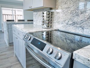 A modern kitchen with a built-in oven, a stainless steel range, and a marble backsplash.