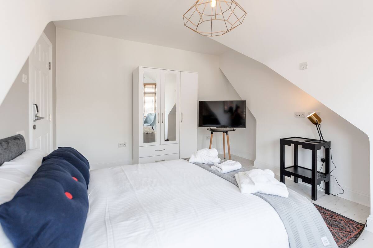 A bedroom with a bed, a wardrobe, a TV, and a lamp.