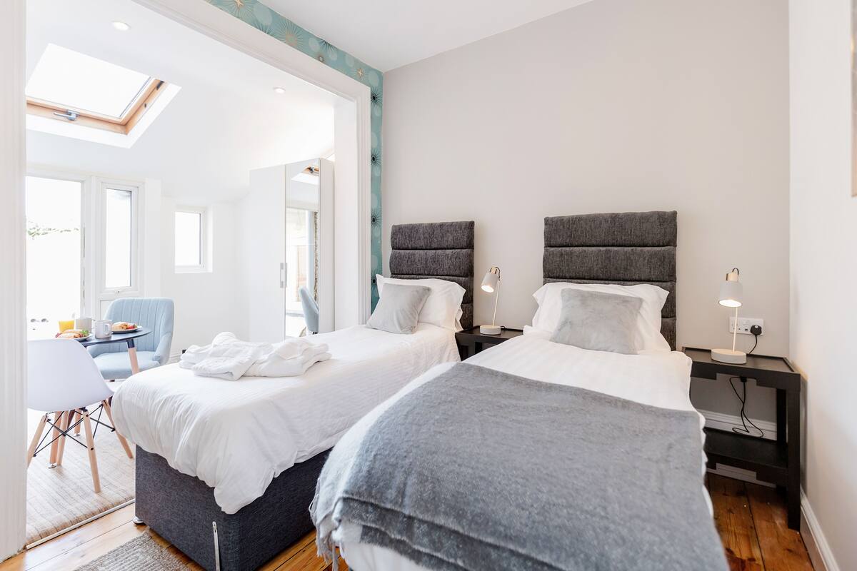 A bedroom with two beds, a skylight, a desk, and a chair.