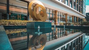 A modern hotel with a reflective pool, large decorative rings, and a brick facade. - The Upper House Hotel (Simpang Ampat)