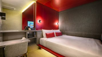 Habitación de hotel con cama, escritorio, silla, televisor y cafetera.