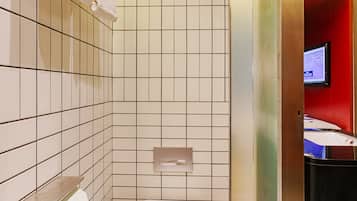 Et lille badeværelse med toilet, skraldespand og håndklædestige.