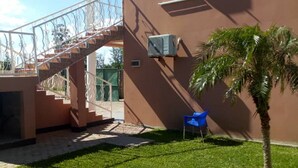 A building with a staircase, a palm tree, and a blue chair in the yard. - Kamuboola Lodge (Choma)