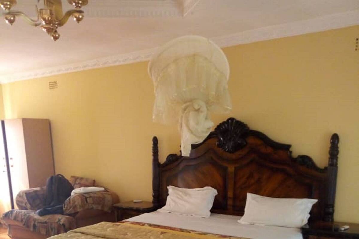 A room with a large bed, a wooden floor, a chandelier, and a wardrobe.