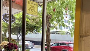 A hostel window with a sign reading "LEMON SIAM HOSTEL" and a view of the street outside. - Lemon Siam Hostel Free Breakfast (Bangkok)