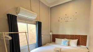 A hotel room with a bed, a window with curtains, a ceiling fan, and a wall-mounted air conditioner. - Lemon Siam Hostel Free Breakfast (Bangkok)