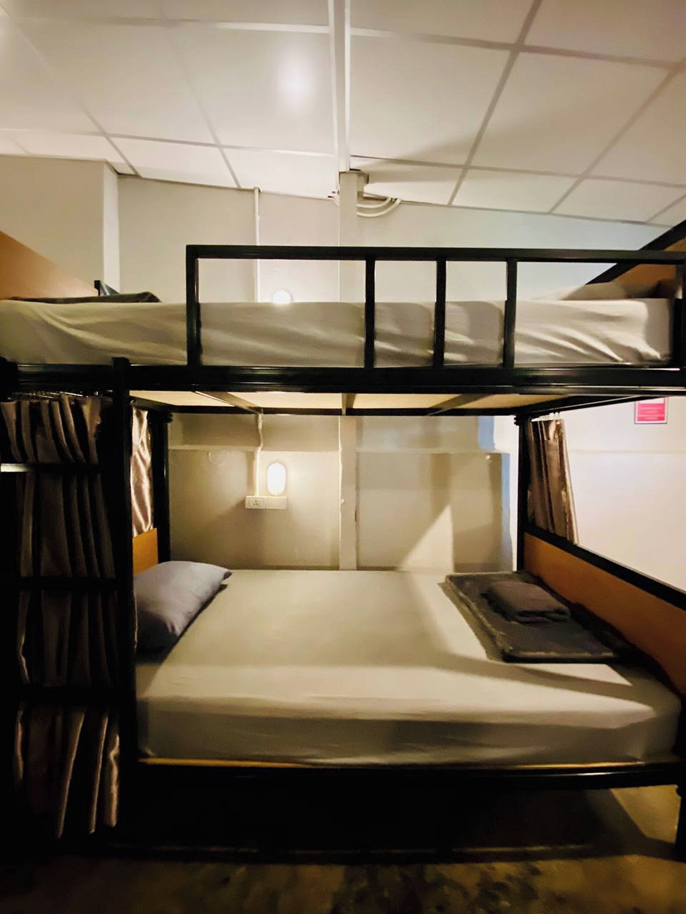 A bunk bed room with a window, curtains, and a small table.
