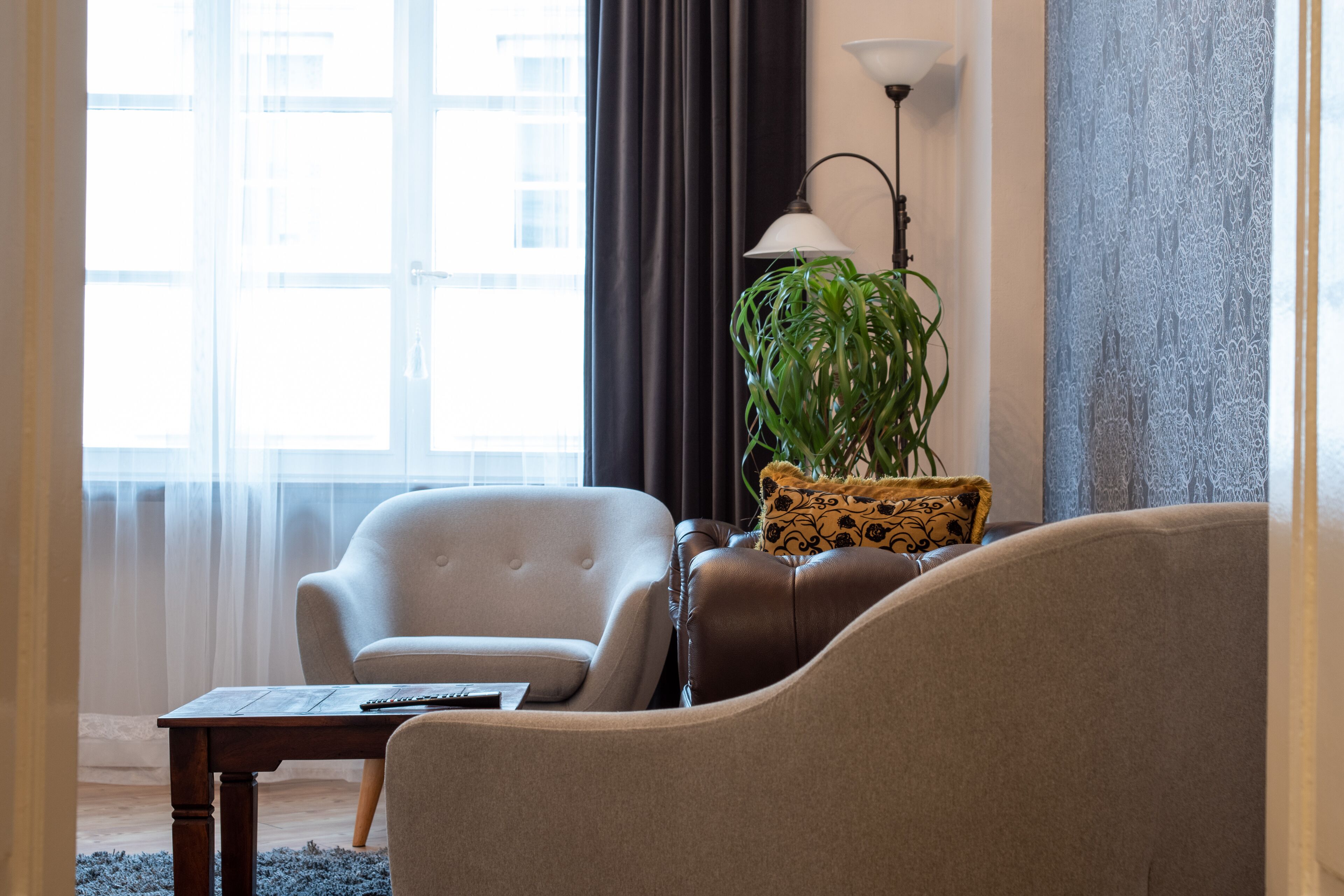 Una sala de estar con un sofá, un sillón y una mesa con un control remoto.