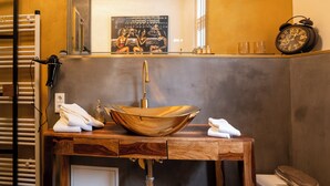 A bathroom with a wooden vanity, a large copper sink, a mirror, and a clock on the wall. - Das Haus Am Markt (Traben-Trarbach)