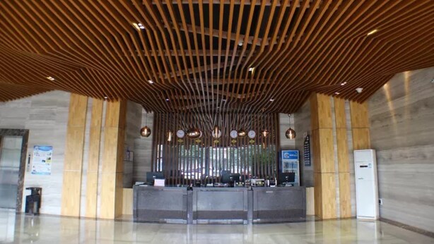 A reception area with a modern wooden ceiling, a reception desk, and a digital information board. - Vyluk Hotel Renmin 3rd Road Qingyuan (Qingyuan)