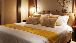 A neatly made bed with white and yellow bedding, a decorative wall with floral and bird motifs, and a warm ambient light source. - Vyluk Hotel Renmin 3rd Road Qingyuan (Qingyuan)