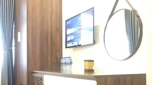 Une chambre moderne avec un bureau en bois, un petit banc, un téléviseur fixé au mur et un miroir.
