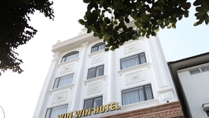 Un hôtel à la façade blanche, sur lequel on peut lire l’inscription « WIN WIN HOTEL ».