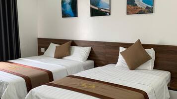 A hotel room with two beds, a wooden headboard, and three framed pictures on the wall.