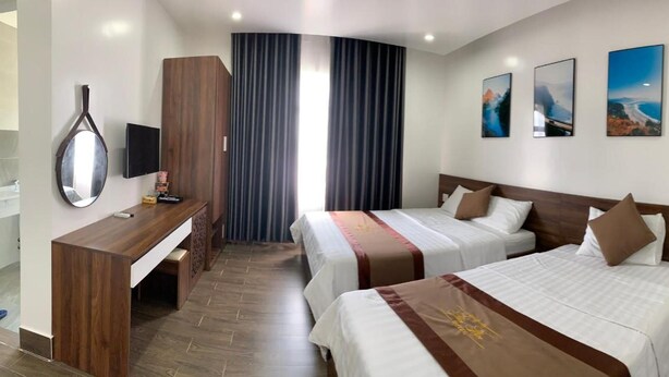 Une chambre d’hôtel avec deux lits, un bureau, un miroir et trois tableaux encadrés accrochés au mur.