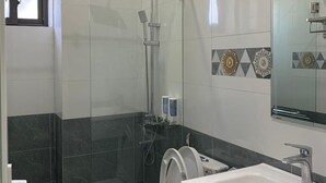 Une salle de bain moderne avec une douche à parois de verre, un lavabo blanc et des toilettes.