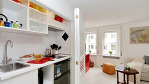 Eine moderne Küche mit weißen Schränken, einem eingebauten Ofen und einer Essecke mit einer Couch und einem kleinen Tisch.