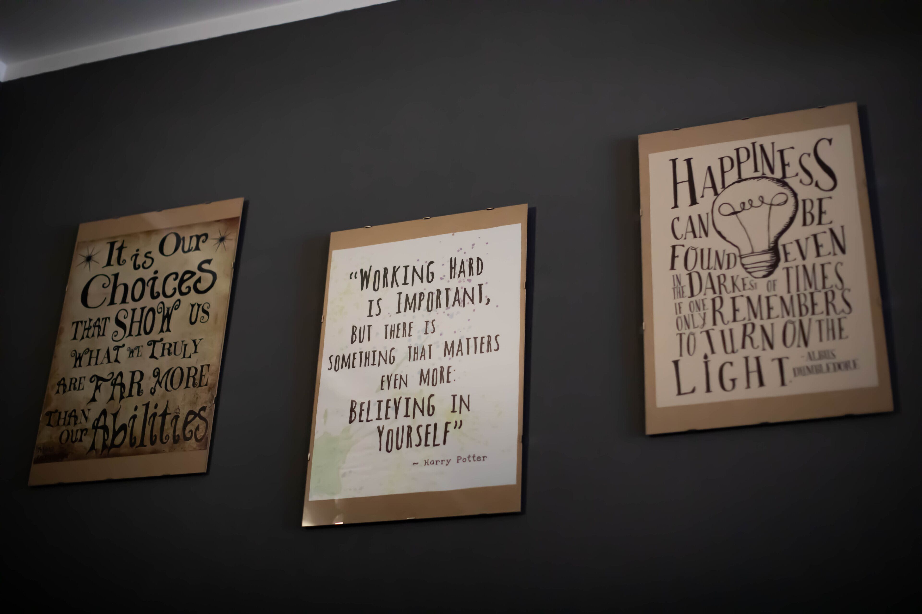 Tres carteles motivacionales sobre una pared oscura.