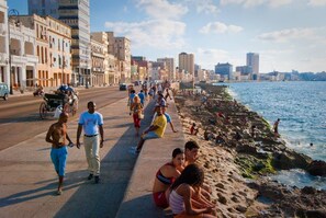 A coastal promenade with people walking and sitting along the beach, overlooking the sea. - Calle Habana Colonial Home 2 - Old Havana (Havana)