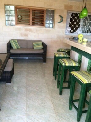 Cozy living space with a sofa, table, and bench. The kitchen area features a sink and counter with bar stools.