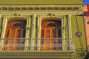 Enjoy the view from this balcony with ornate railings and windows with wooden shutters.