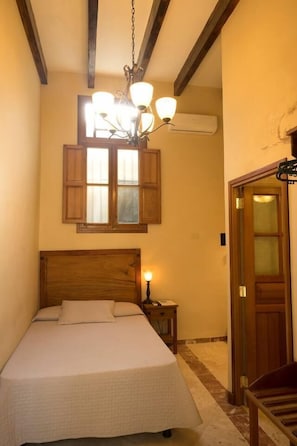 Relax in this serene bedroom with a large bed, chandelier, and wooden shutters.