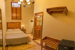 Traditional hotel room with a wooden bed, bedside table, and wooden shelf.