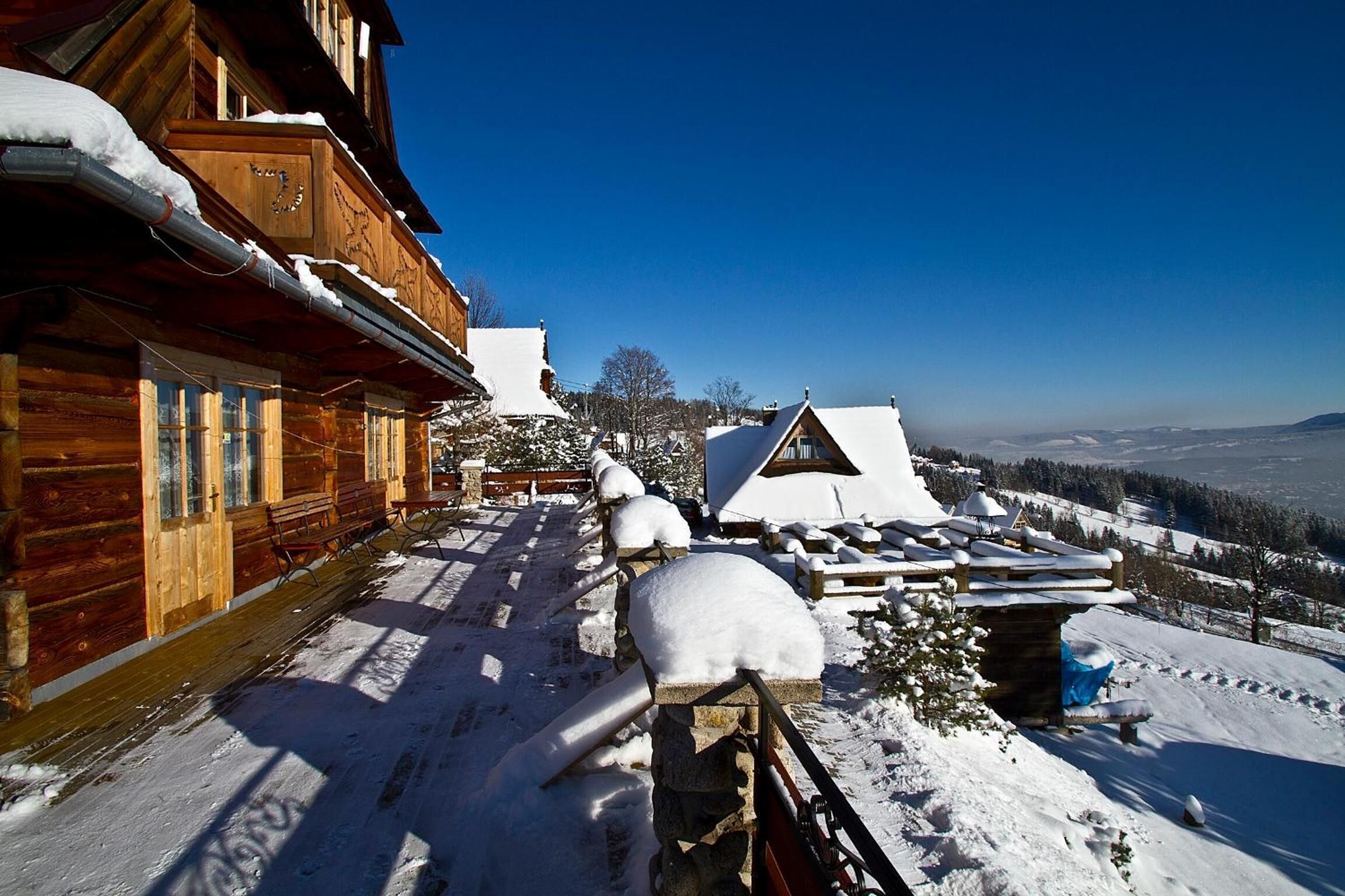 Uma cabana de madeira com telhado coberto de neve e um deck de madeira.