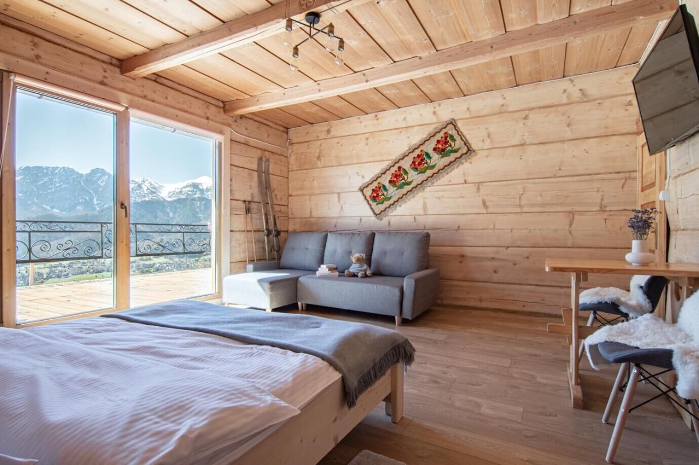 Een houten kamer met een bed, een slaapbank en een tafel met stoelen.