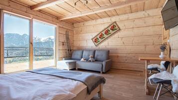 Een houten kamer met een bed, een slaapbank en een tafel met stoelen.