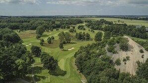 An aerial view of a golf course with multiple greens, sand bunkers, and a variety of trees. - Södersens Golf Lodge (Billesholm)