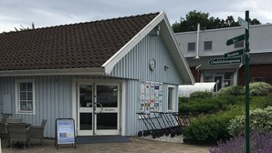 A building with a tiled roof, a reception desk, and a signboard with various logos. - Södersens Golf Lodge (Billesholm)