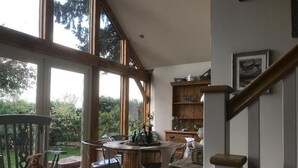 Un espace repas avec une table ronde, des chaises et une vue sur la verdure environnante.
