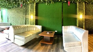 A seating area with two sofas and a small table, green walls, and a wooden floor. - Brighams Suites (Lagos)